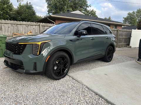 Green Kia Sorento with ceramic coated paint and gloss black wheels on a gravel drive