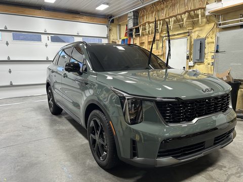 Green Kia Sorento with a fresh ceramic coating reflecting the shop lights