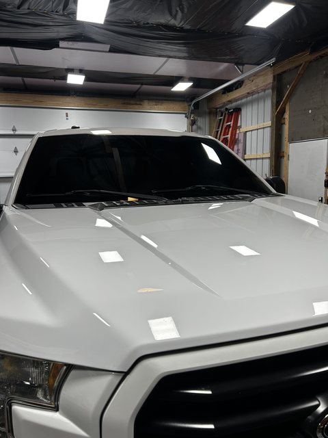 Front of a silver pickup with ceramic coated paint reflecting the shop lights